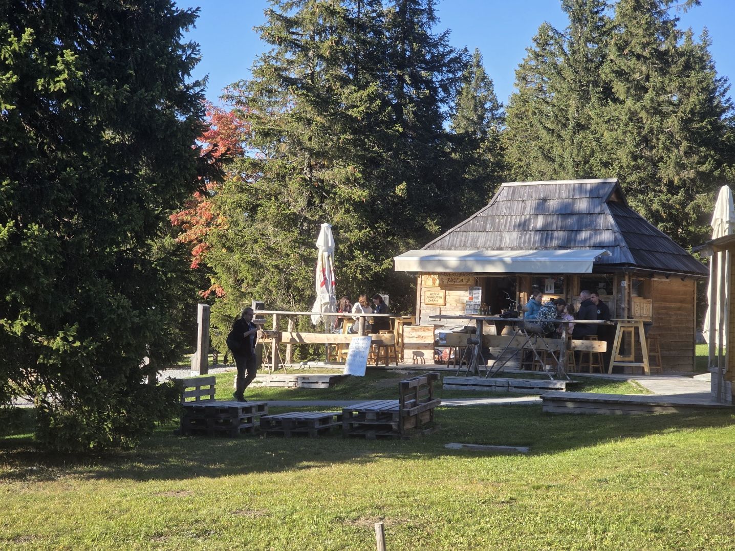 Kućica pohorskih delicija u jesen, gosti na terasi među smrekama